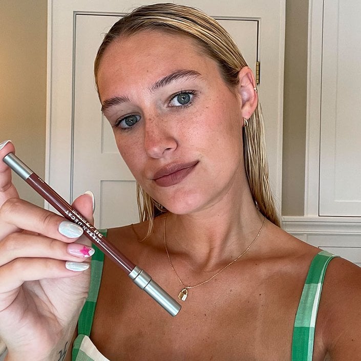 Editor with long blonde hair wearing and holding up the Urban Decay 24/7 Glide-On Lip Pencil in 1993