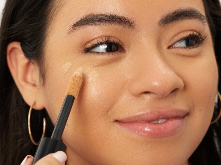 Close-up picture of a person applying concealer on cheekbone