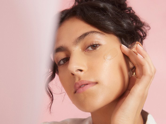 person with dark hair touching their finger to their cheek