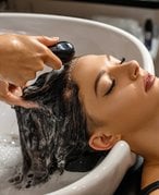person getting their hair washed in a shampoo bowl