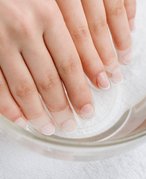 Image of a person's hands soaking in a bowl of clear liquid