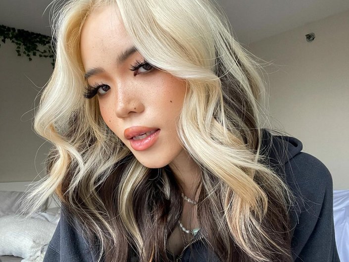 Person with contrasting blonde and dark hair styled in wavy layers 