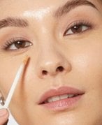 A person applying a concealer to cheek