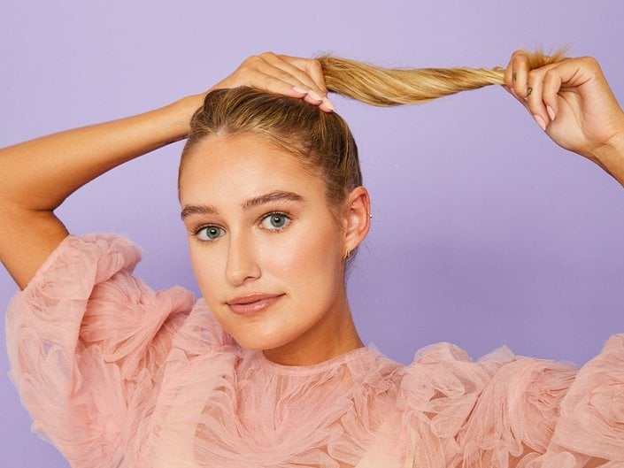 photo of person creating a messy bun on purple background