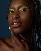 Photo of person with green eyeshadow and pouty lips on a dark blue background.