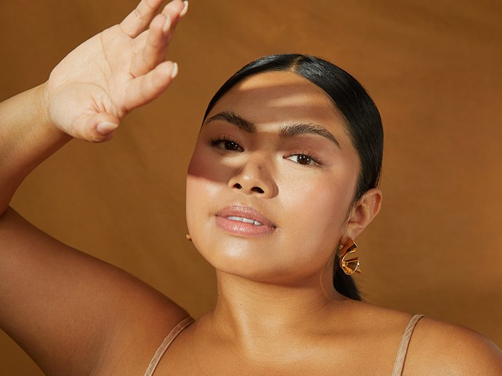 person smiling at the camera holding their hand up to block the light