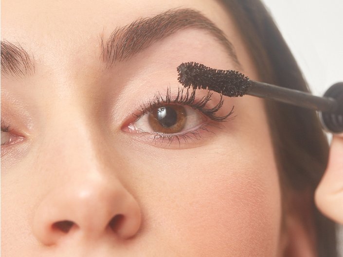 person holding mascara wand up to eyelashes