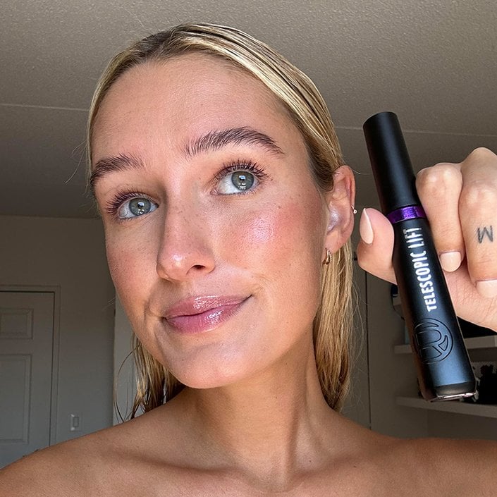 Editor wearing and holding up the L’Oréal Paris Telescopic Lift Washable Color Mascara in Galactic Purple