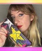 Picture of the editor holding the Urban Decay Naked Metal Mania Eyeshadow Palette on a pink and yellow gradient graphic background