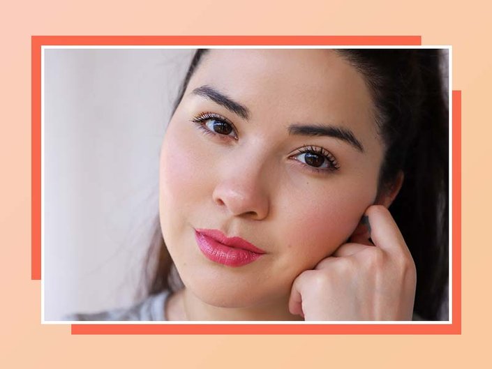 Close-up of a person with dark hair wearing natural makeup and pink lipstick